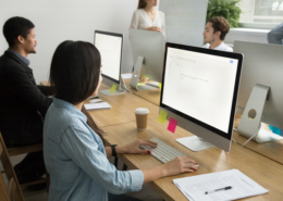 Multiracial colleagues working together on desktop computers in